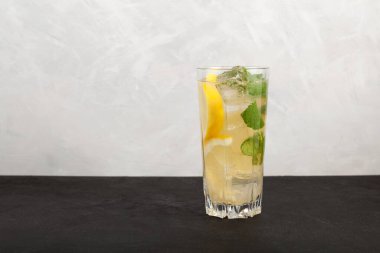 Büyük bardakta ev yapımı buzlu limonata. Limon ve nane yapraklı yaz içeceği. Gri arkaplan, metin için boşluk.