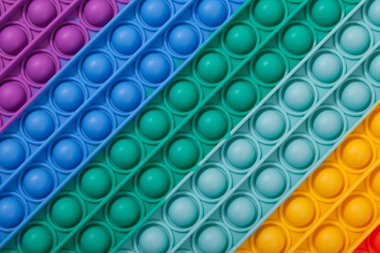 Çok renkli lastik çocuk oyuncağı POP IT 'in yüzeyi, yakın plan. Kabarcığa dokun, parmak oyunu.