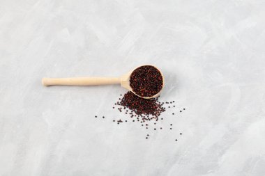 Ragi veya siyah kinoa gri arka planda tahta kaşıkta, seçici odak, kopyalama alanı. Organik tahıllar büyük miktarda protein, antioksidan, diyet lifleri, vitaminler ve mineraller içerir..