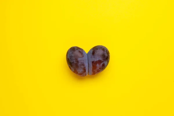 Ugly plum. Yellow background, copy space. Fused fruits, double prunes. Concept - Using for eating imperfect products. Food waste reduction.