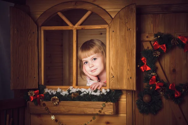 Little girl in wooden house with christmas decoration