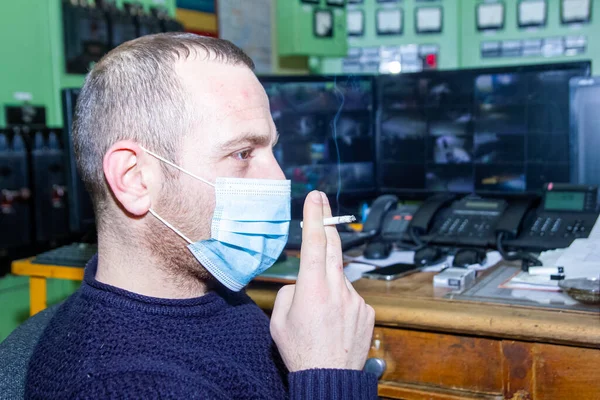 engineer with medical mask at work smoking cigarette