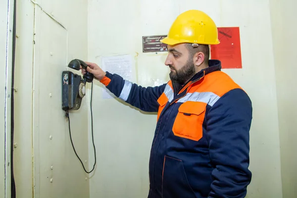 electrician with yellow helmet at work in a power station talking on phone, electrician at work