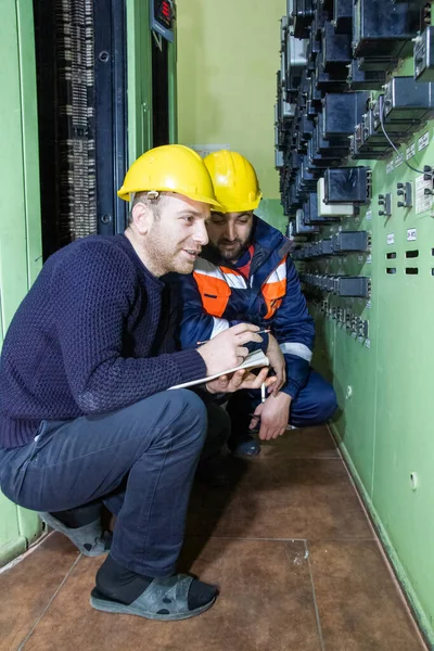 Electricistas Con Casco Amarillo Trabajando Una Central Eléctrica Imagen de archivo