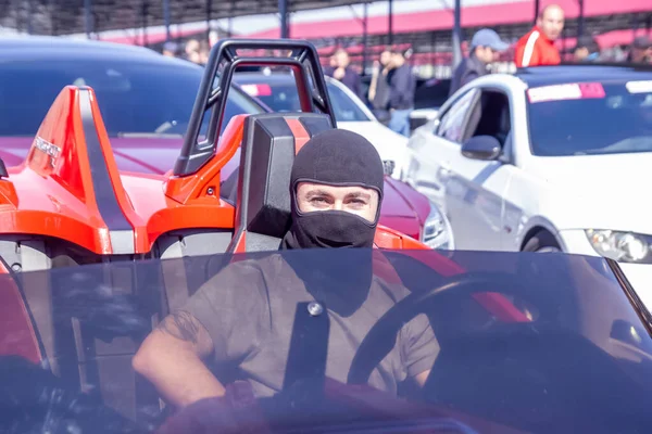 view of a person driving a car, man with black mask in the car