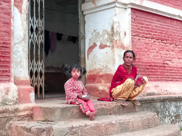 mother and daughter are sitting on the stairs, mother and daughter are sitting in front of a house