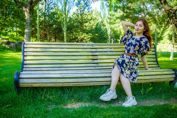 女人坐在公园的长椅上 女人坐在木制长椅上 — 图库照片