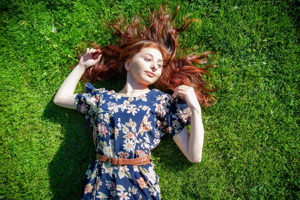 公園の赤い髪の女性草のきれいな女性草の上に寝そべっているきれいな女性 — ストック写真