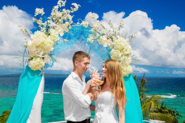 Mavi bir tropik sahilde düğün töreni. Mutlu damat ve br