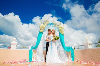 Mavi bir tropik sahilde düğün töreni. Mutlu damat ve br