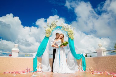 Mavi bir tropik sahilde düğün töreni. Mutlu damat ve br