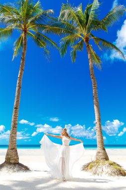 Young beautiful bride in white wedding dress under the palm tree
