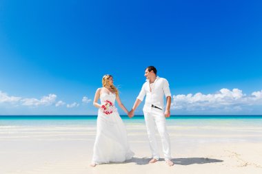 Happy bride and groom having fun on a tropical beach. Wedding an clipart