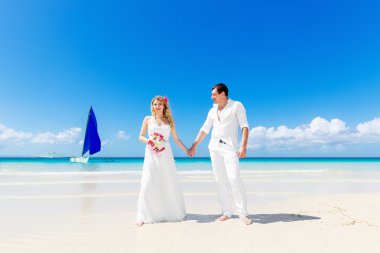 Mutlu gelin ve damat bir tropik sahilde eğleniyor. Düğün bir