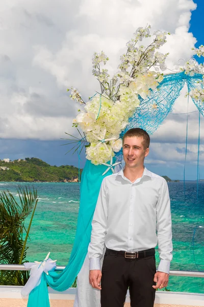 De ceremonie van het huwelijk op een tropisch strand in blauw. Wacht totdat de bruidegom — Stockfoto