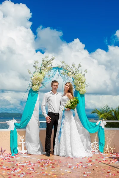 De ceremonie van het huwelijk op een tropisch strand in blauw. Gelukkige bruidegom en br — Stockfoto