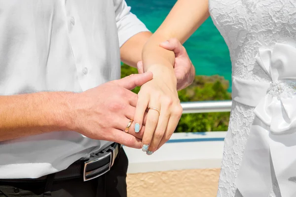 Mãos masculinas e femininas com anéis de casamento sob o arco decorar — Fotografia de Stock