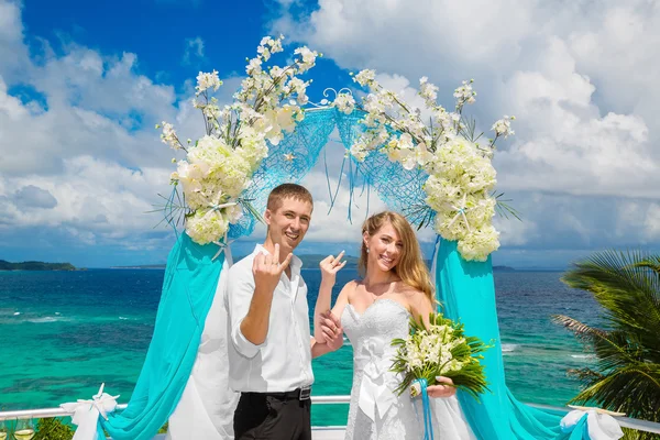 Noivo feliz e noiva com anéis de casamento sob o arco decorar — Fotografia de Stock