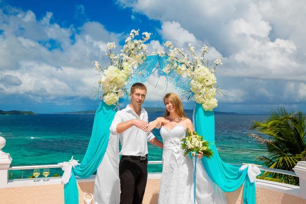Felice sposo e sposa con fedi nuziali sotto l'arco decorare — Foto Stock