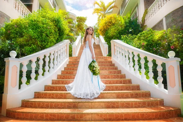 Mooie bruid in bruiloft jurk met lange trein staande op de — Stockfoto