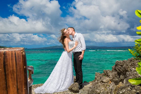 Happy bride and groom having fun on a tropical beach under the p — Stock Photo, Image