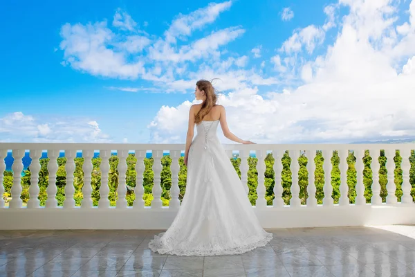 Gelukkige bruid staat naast het stenen prieel temidden van prachtige tro — Stockfoto