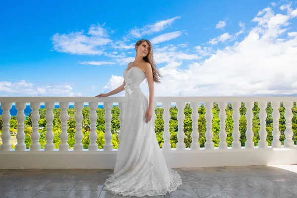 Happy bride standing next to the stone gazebo amid beautiful tro — Stock Photo, Image