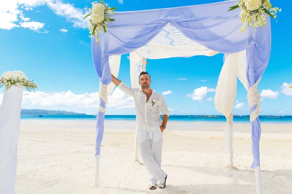 De ceremonie van het huwelijk op een tropisch strand in blauw. Wacht totdat de bruidegom — Stockfoto