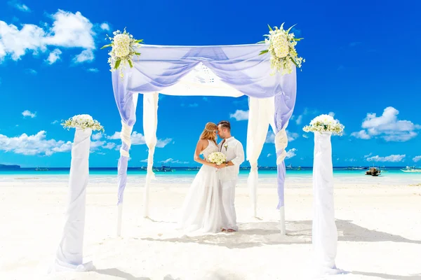 De ceremonie van het huwelijk op een tropisch strand in wit. Gelukkige bruidegom en b — Stockfoto