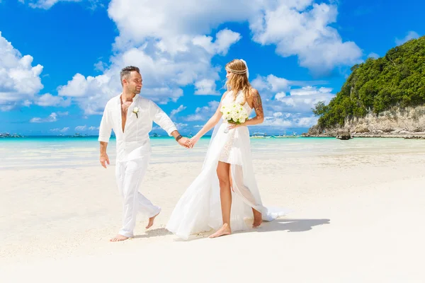 Счастливая невеста и жених веселятся на тропическом пляже. Свадьба — стоковое фото