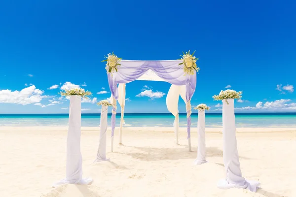 Matrimonio in spiaggia. Arco da sposa decorato con fiori su tr — Foto Stock