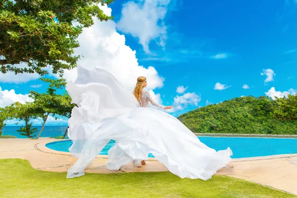 Beautiful bride in wedding dress with long train standing at the — Stock Photo, Image