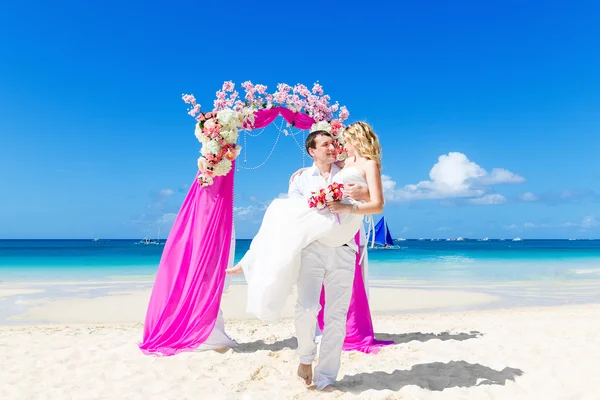 Ceremonia de boda en una playa tropical en púrpura. novio feliz y — Foto de Stock