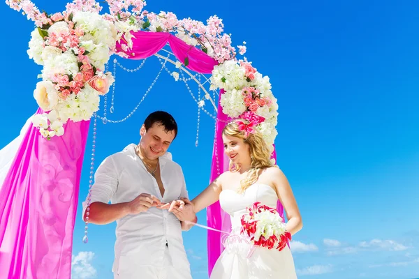 Groom giving an engagement ring to his bride under the arch deco — Stock Photo, Image