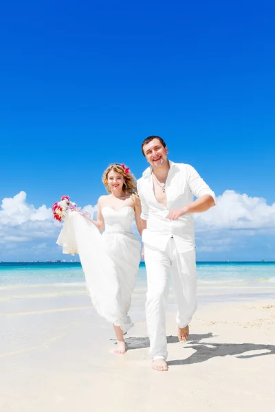 Happy bride and groom having fun on a tropical beach. Wedding an — Stock Photo, Image