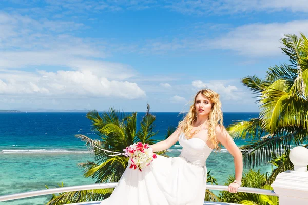 Happy bride standing next to the stone gazebo amid beautiful tro — Stock Photo, Image