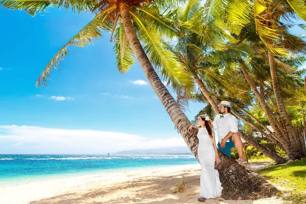 Glückliche Braut und Bräutigam haben Spaß an einem tropischen Strand unter Palmen — Stockfoto