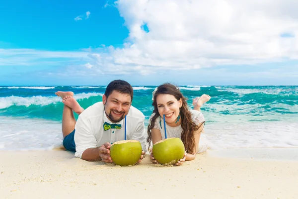 Novia feliz y novio divirtiéndose en una playa tropical con coco — Foto de Stock