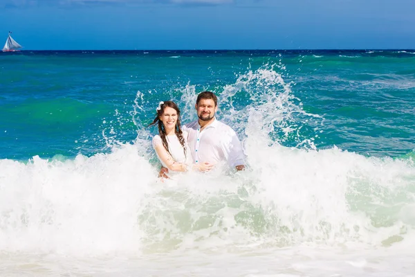 Happy bride and groom having fun in the waves on a tropical beac — Stock Photo, Image
