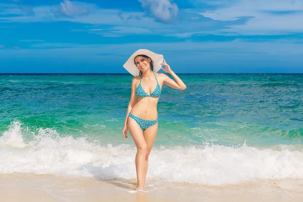 Fiatal gyönyörű lány bikini és fehér szalmakalap a strandon — Stock Fotó