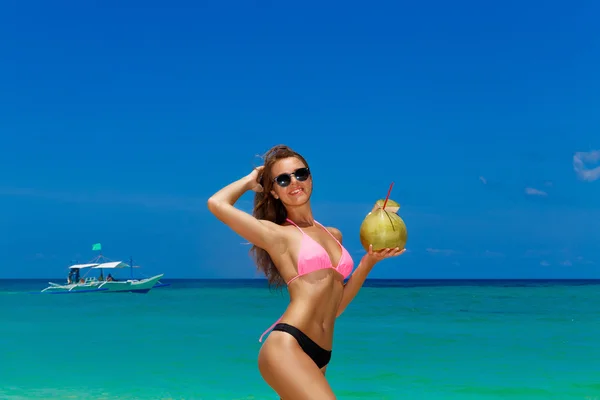 Счастливая молодая девушка в бикини с кокосом в тропиках — стоковое фото