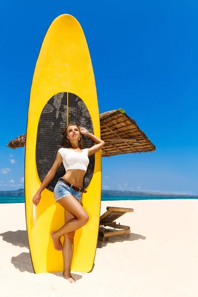 Happy beautiful young girl with paddle board on a tropical beach — Stock Photo, Image