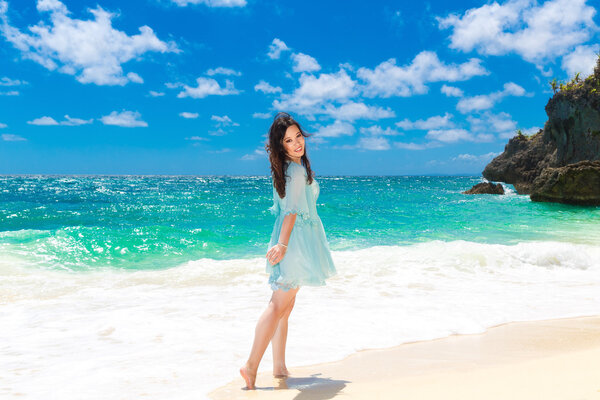 Young beautiful Asian  girl in blue dress on the beach of a trop