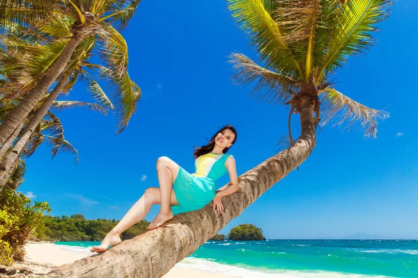 Jonge mooi Aziatisch meisje op de palmboom op een tropisch strand — Stockfoto