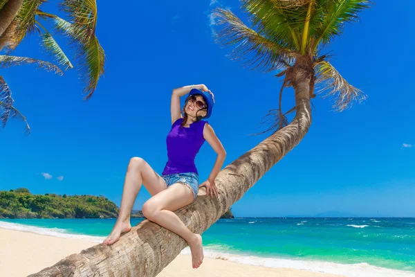 Jonge mooi Aziatisch meisje op de palmboom op een tropisch strand. — Stockfoto