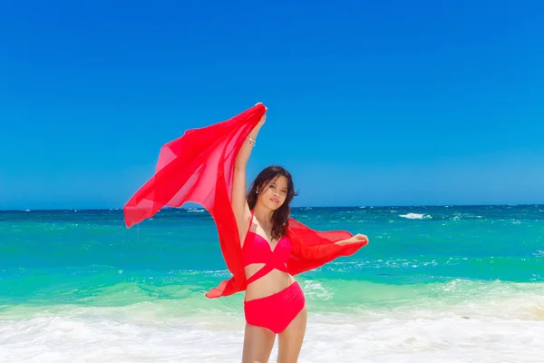 年轻漂亮的亚洲女孩，用红布进港的海滩上 — 图库照片