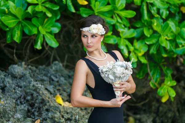 Giovane bella ragazza in tropici con una ghirlanda, tenendo una bouque — Foto Stock