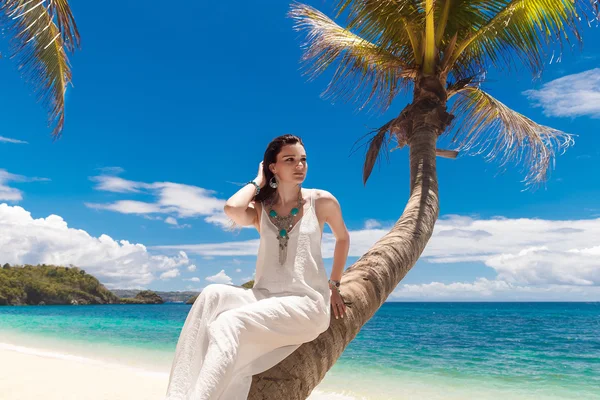 Jonge mooie bruid in witte jurk op de palmboom op een tropi — Stockfoto