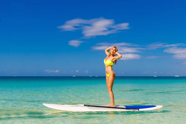 Joyeux belle jeune fille avec planche à pagaie sur une plage tropicale — Photo