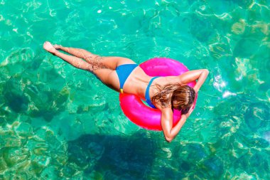 Genç güzel kız bikini bir tropikal deniz rubb üzerinde yüzüyor.